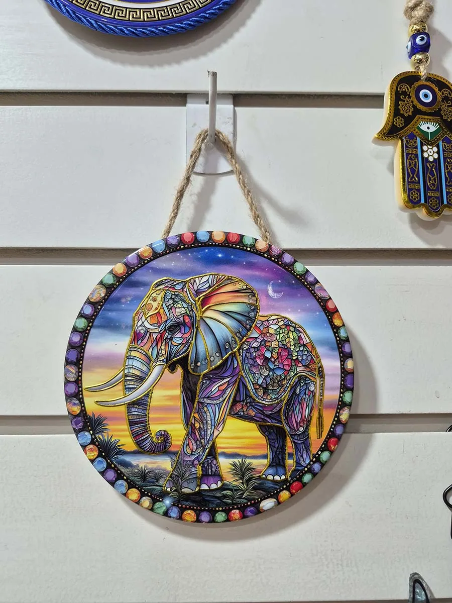 Colgante de pared redondo de cerámica con elefante colorido sobre un paisaje de anochecer