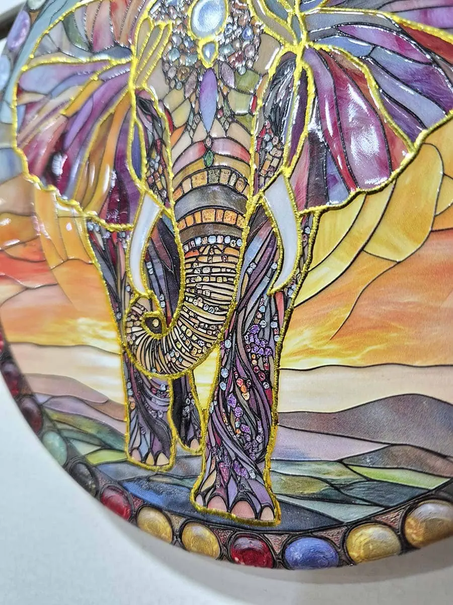 Colgante decorativo de pared de cerámica con un elefante sobre un paisaje de amanecer en tonos cálidos