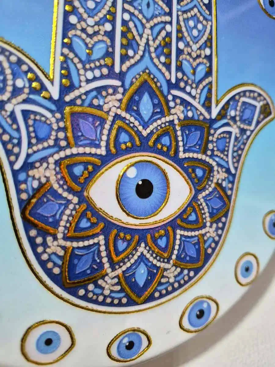 Colgante decorativo redondo de cerámica con Mano de Fátima y ojos turcos sobre fondo celeste