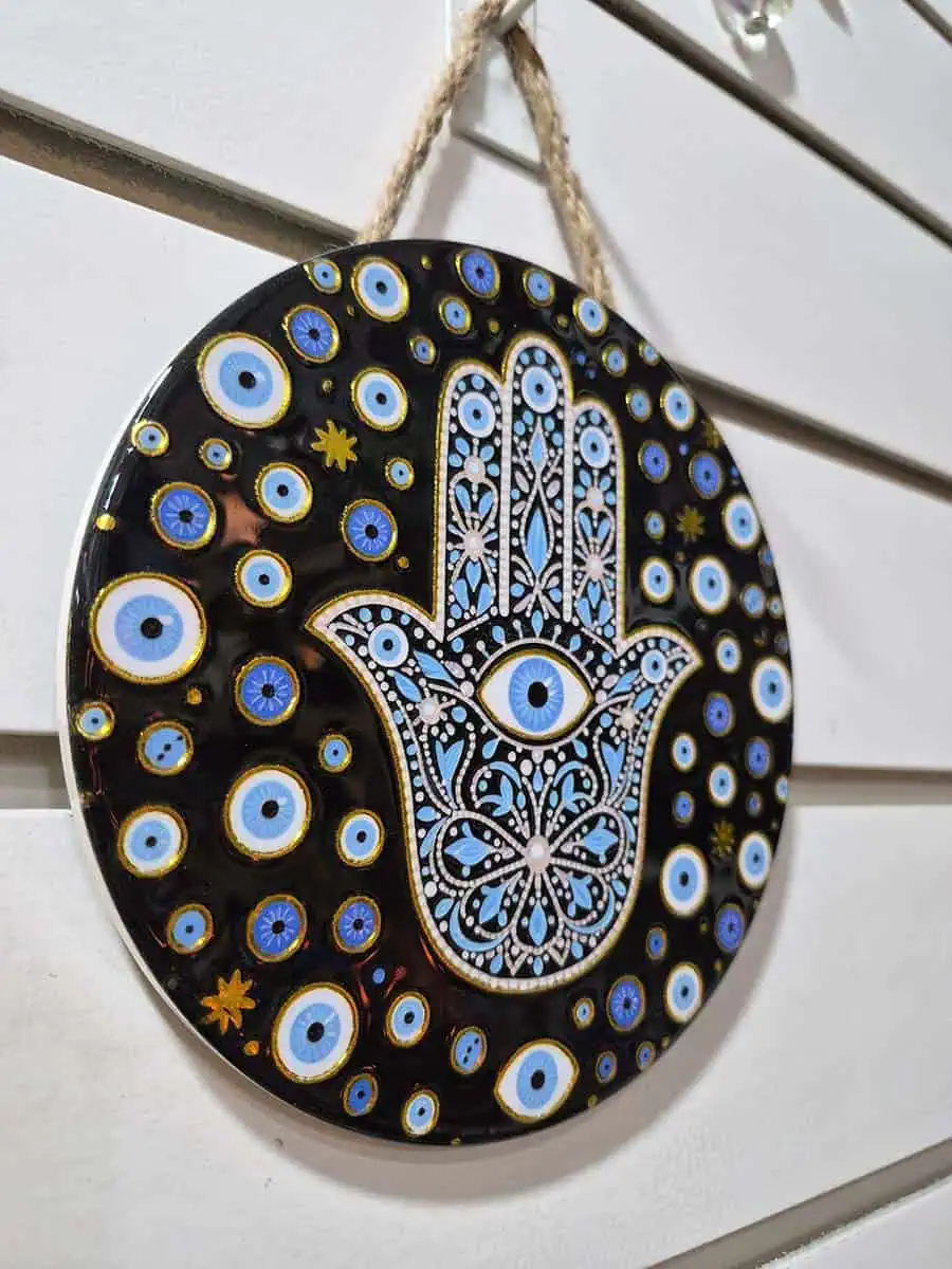 Colgante decorativo redondo de cerámica con Mano de Fátima y múltiples ojos turcos sobre fondo negro