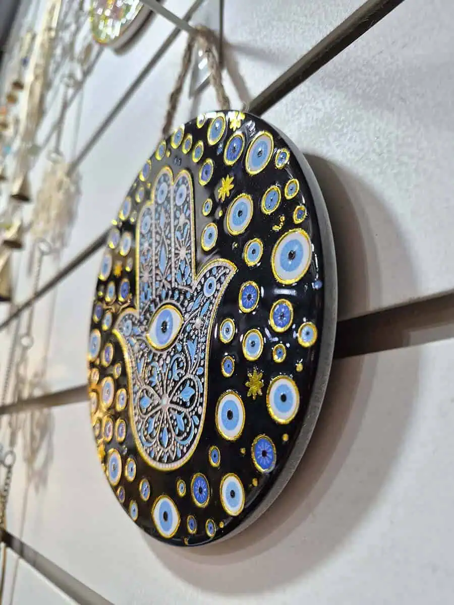 Colgante decorativo redondo de cerámica con Mano de Fátima y múltiples ojos turcos sobre fondo negro