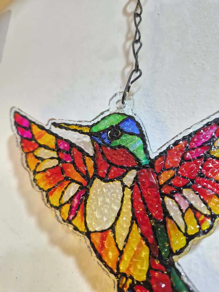 Colgante decorativo de colibrí en vitró rojo y rosa con detalles amarillos y campana de metal