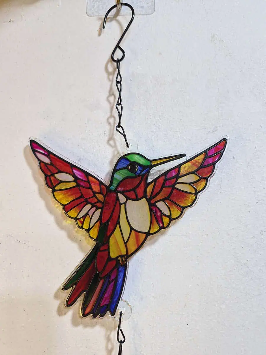 Colgante decorativo de colibrí en vitró rojo y rosa con detalles amarillos y campana de metal