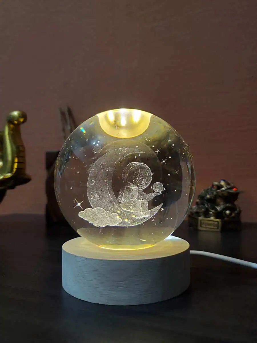 Lámpara esfera de cristal con diseño 3D de un Astronauta sentado en la luna con eschufe USB