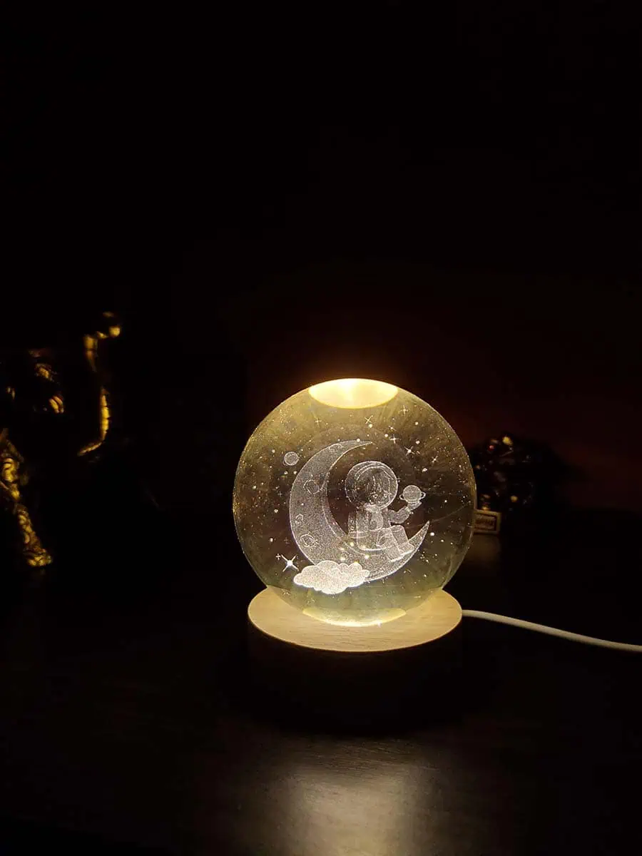 Lámpara esfera de cristal con diseño 3D de un Astronauta sentado en la luna con eschufe USB