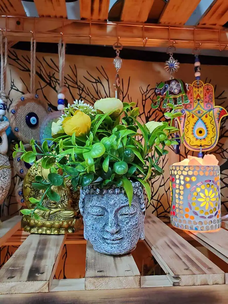 Maceta con cara de Buda con flores amarillas artificiales