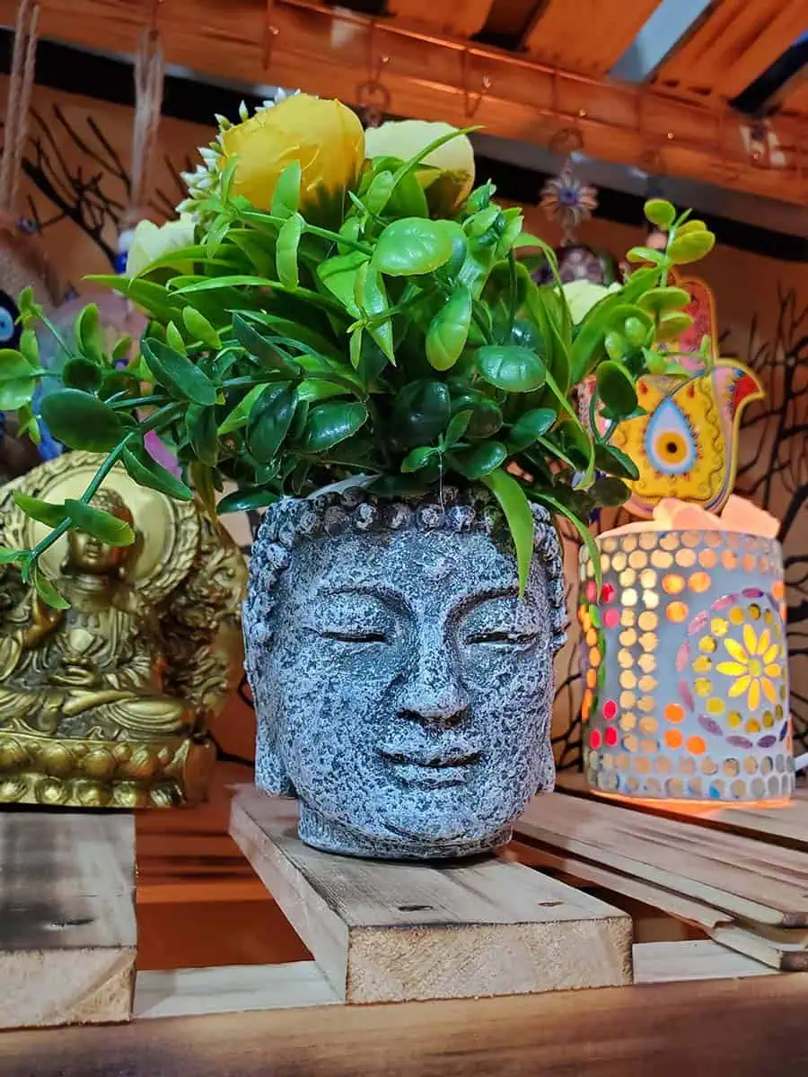 Maceta con cara de Buda con flores amarillas artificiales