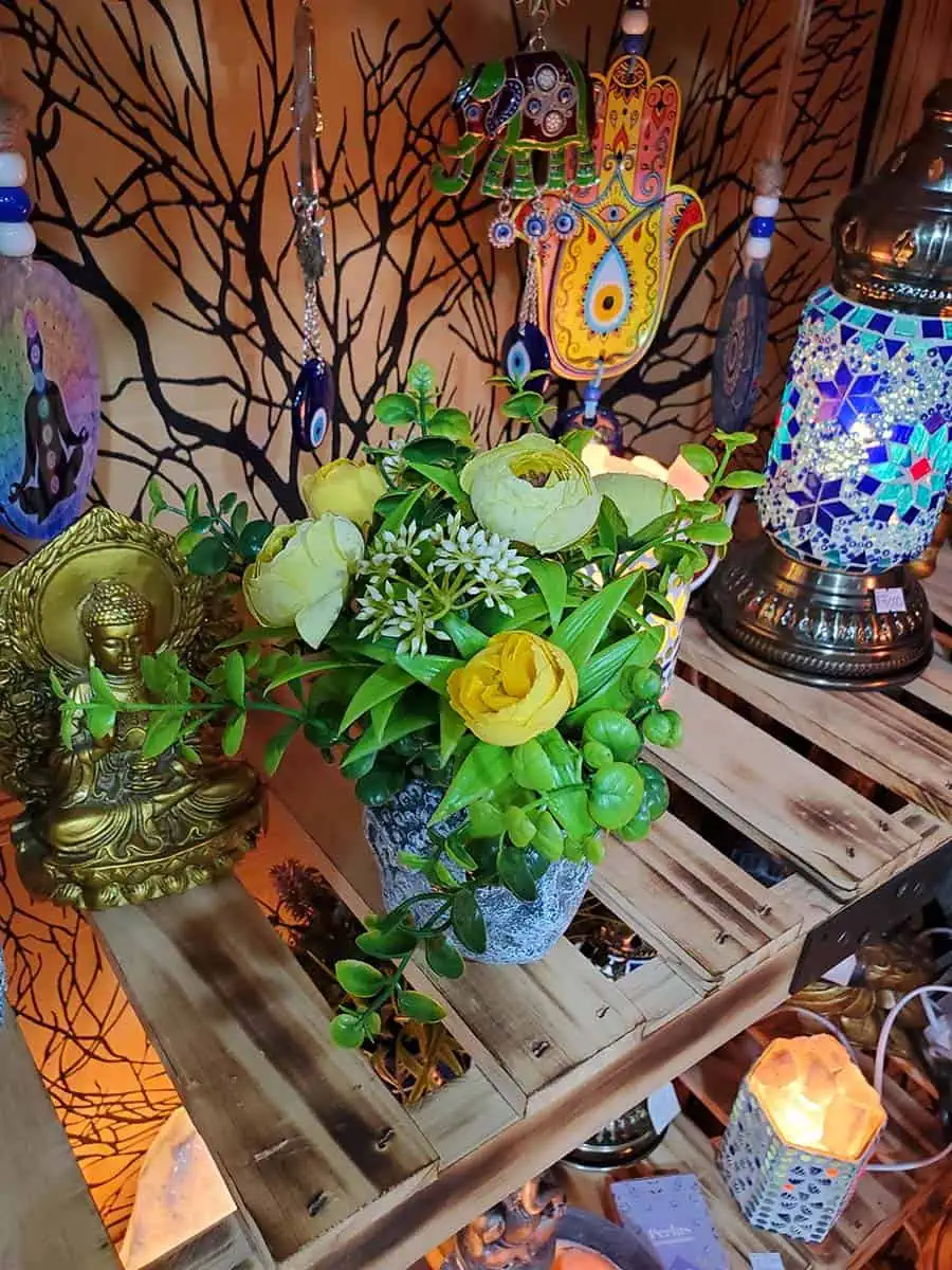 Maceta con cara de Buda con flores amarillas artificiales