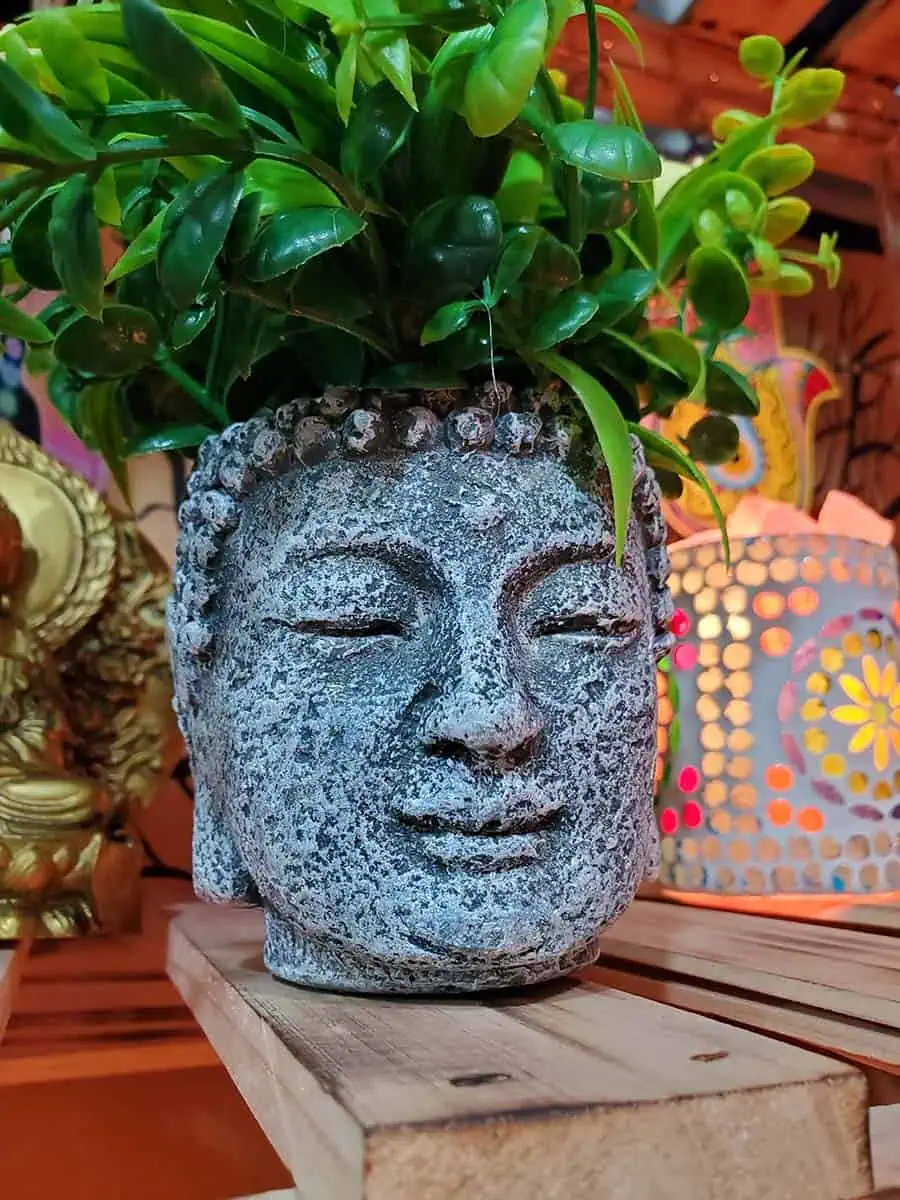 Maceta con cara de Buda con flores amarillas artificiales